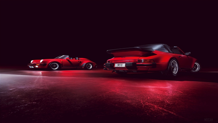 Two red Porsche 911 cars in a dark studio
