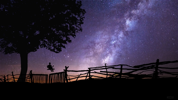 Silhouette of a person on a swing under a starry sky