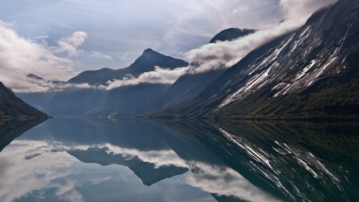 Mountains reflected in a calm lake under a cloudy sky