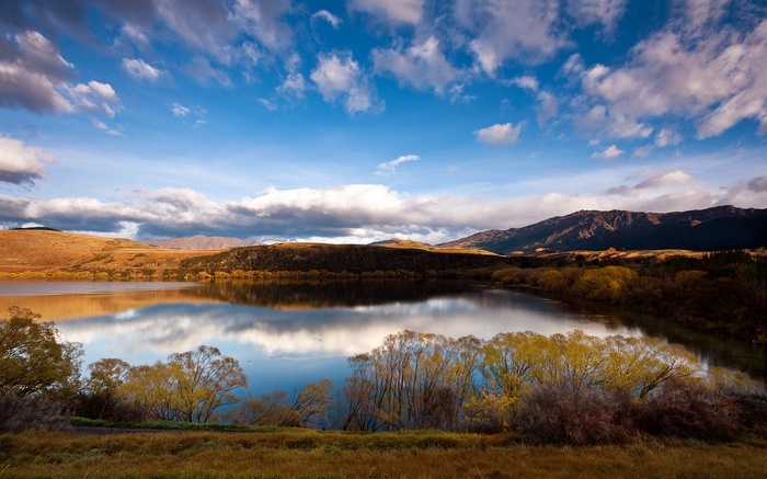 Lake and mountains under a cloudy blue sky