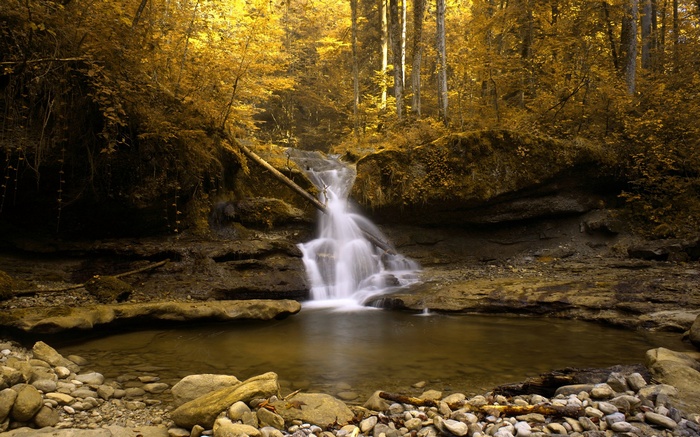 Waterfall in an autumn forest with rocky riverbed
