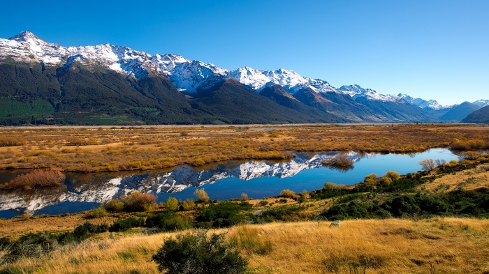 Snow-capped mountains reflected in a calm river