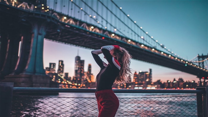 Woman with hands in hair near bridge in 4K