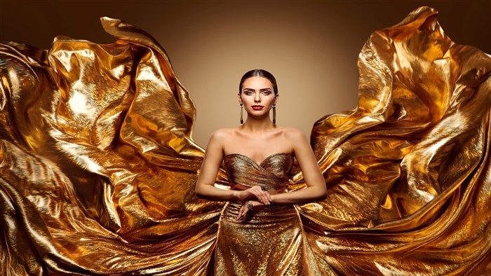 Model in a golden dress with flowing fabric