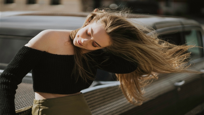 Girl blowing hair near a car