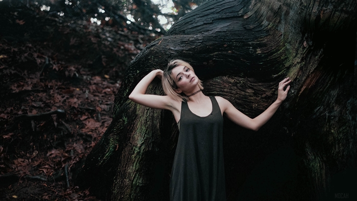 Girl posing by a large tree in a forest 4K