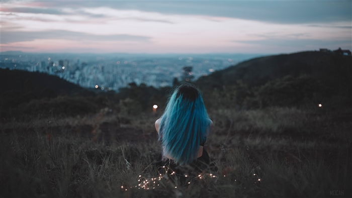 Woman with Blue Hair Sitting on Grass Field at Dusk
