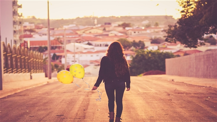 Girl with yellow balloons walking away