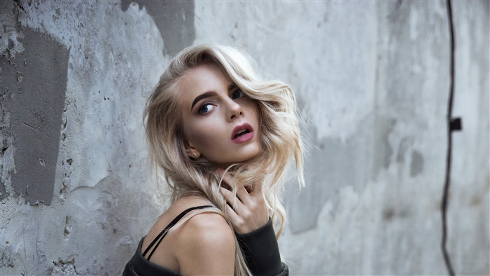 Blonde woman posing against a concrete wall