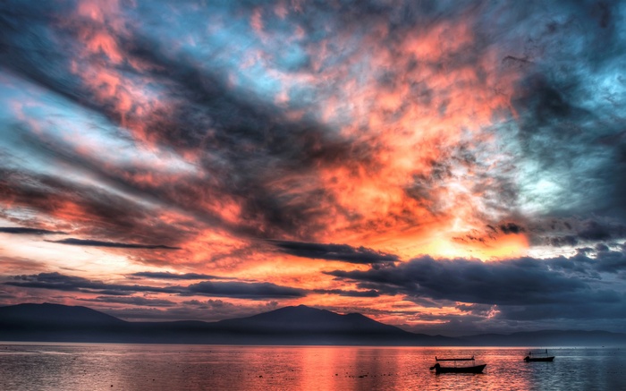 Dramatic sunset over a calm lake with mountains