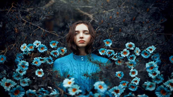 Woman in blue sweater surrounded by blue flowers