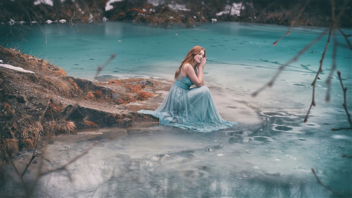Woman in blue dress by icy lake