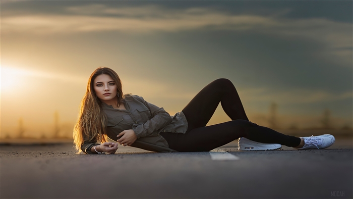 Girl lying on the road at sunset