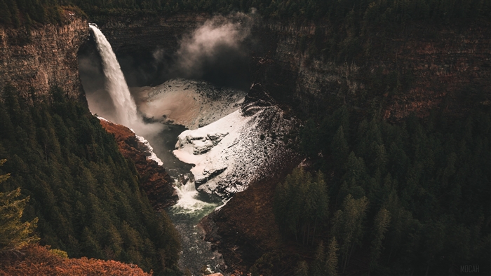 Waterfall in a canyon with snow and trees