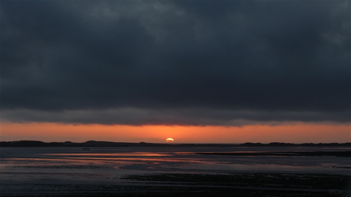 Sunset over water with dark clouds