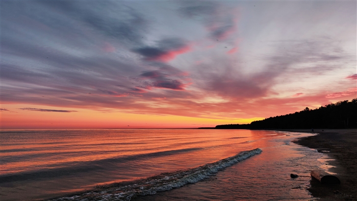 Sunset over a beach with calm ocean waves