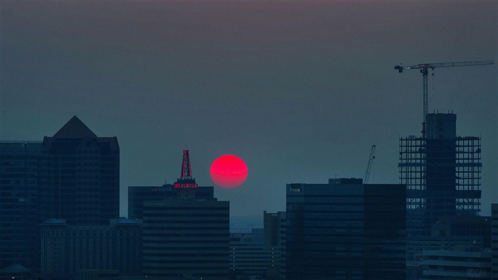 Red Sun Over City Skyline with Cranes