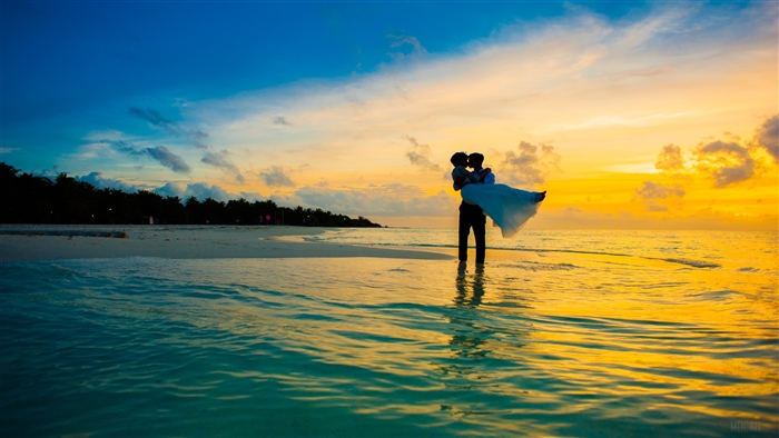 Man carrying woman on beach at sunset 4K
