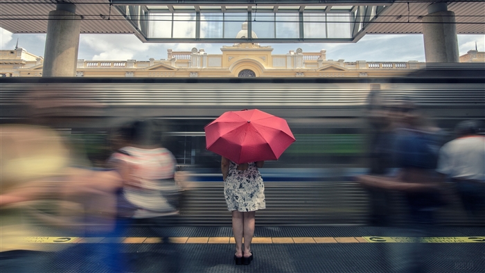 Woman with red umbrella on train platform