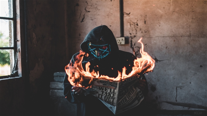 Person in mask burning newspaper