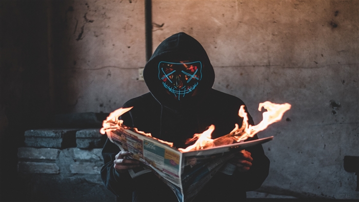 Masked person reading burning newspaper 4K