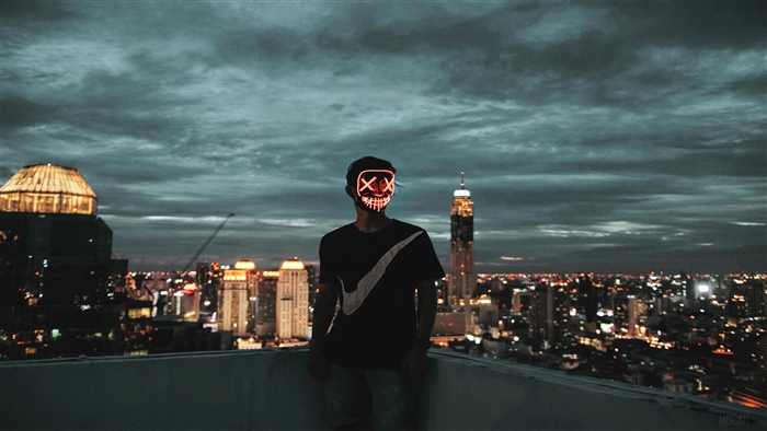 Man in Neon Mask on Rooftop Overlooking City