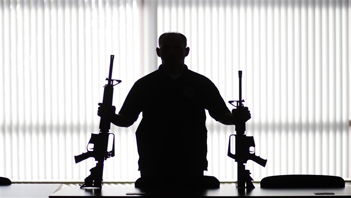 Man holding two rifles in silhouette