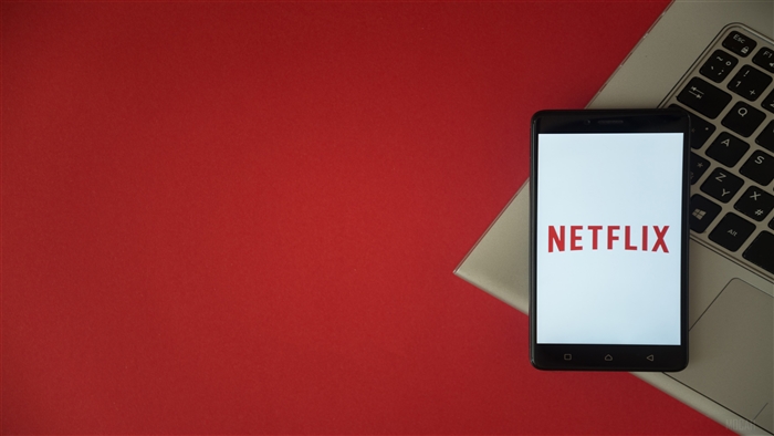 Netflix logo on a smartphone with laptop