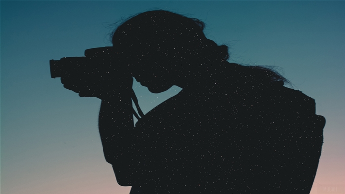 Silhouette of a person taking a photo with a DSLR camera