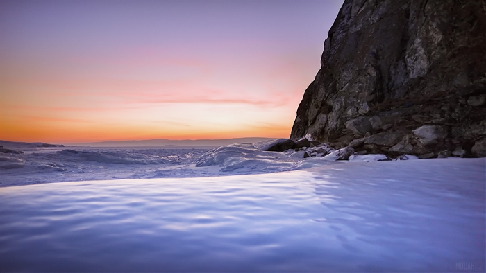 Frozen Sea Shore with Rocky Cliff at Sunset 4K