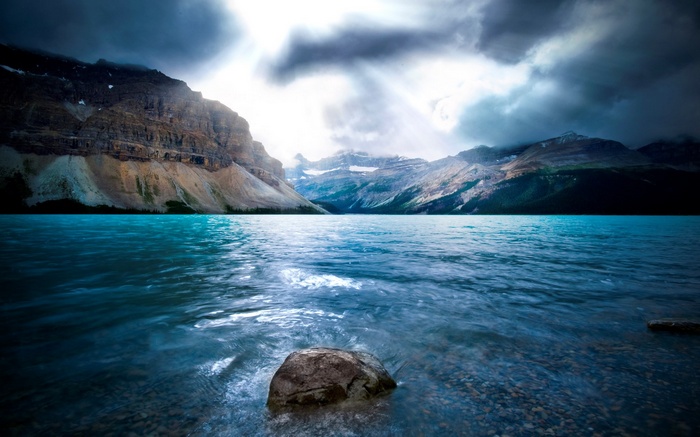 Turquoise lake and mountains under stormy sky