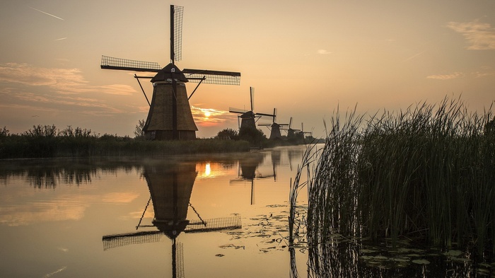 Windmills reflected in water at sunrise
