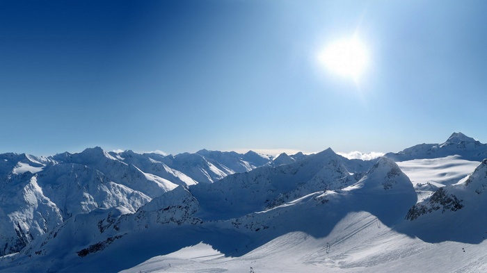 Snowy mountain range under a bright sun