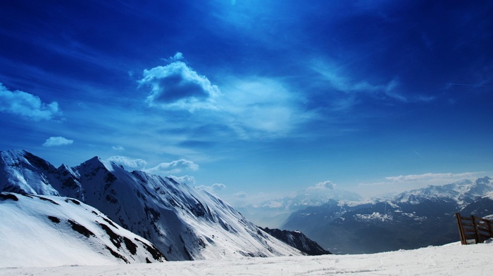 Snowy mountains under a blue sky with clouds