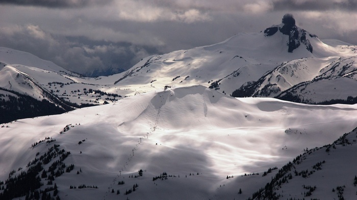Snowy mountains with dramatic clouds and a prominent peak