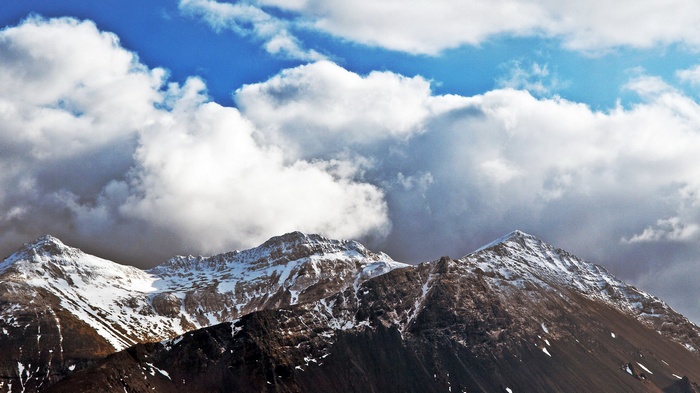Snow-capped mountains under a cloudy blue sky