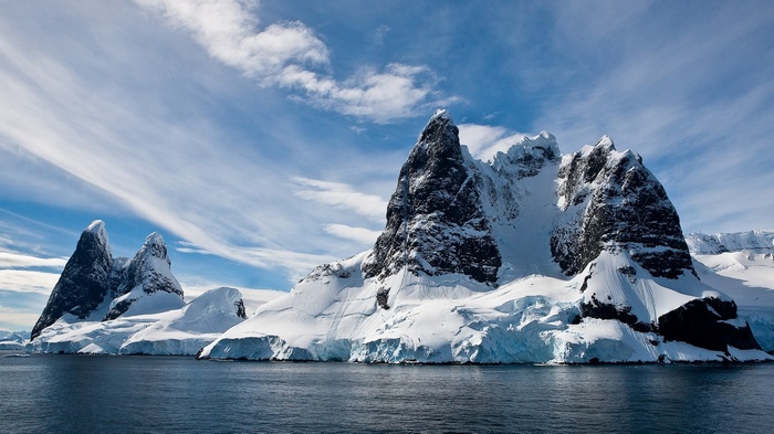 Snow-covered mountains and sea under a cloudy sky