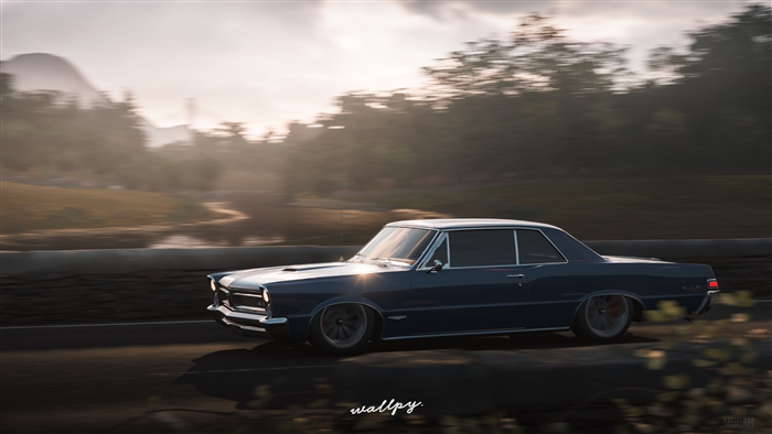 Blue 1960s Pontiac GTO driving on a road