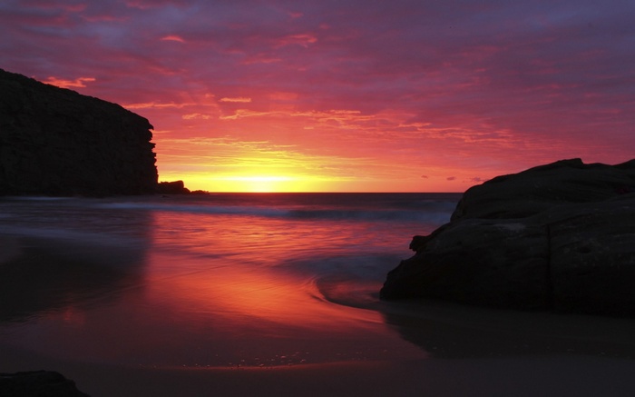 Sunset over a rocky beach with colorful clouds
