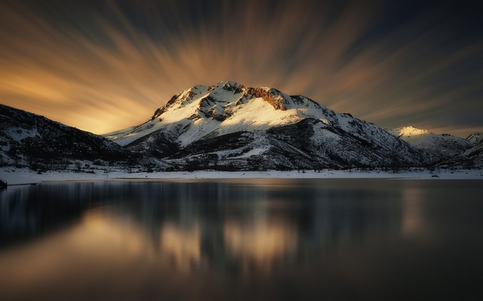 Snowy mountains reflected in a lake at sunset