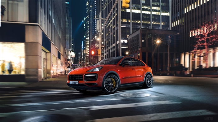 Orange Porsche Cayenne Coupe driving in city at night