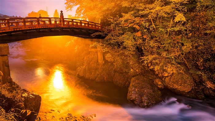 River flowing under a bridge with autumn trees