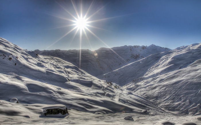 Sun shining over snow-covered mountains