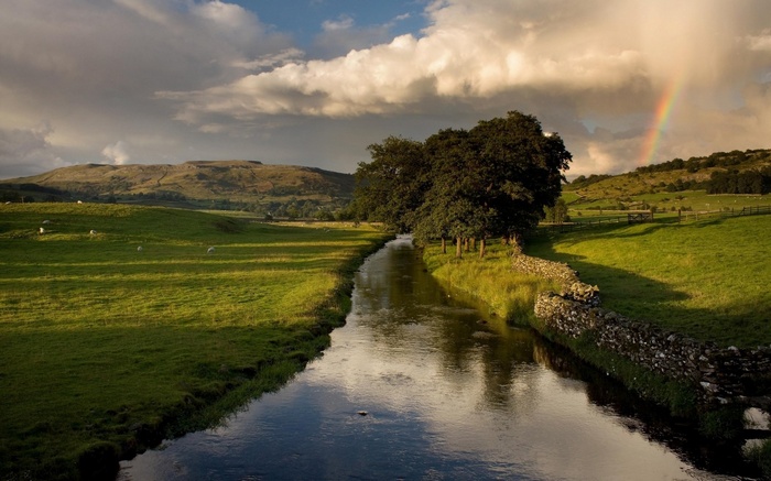 River flowing through green fields with a rainbow
