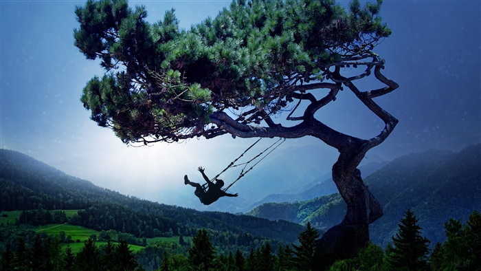 Silhouette of a boy on a swing under a tree