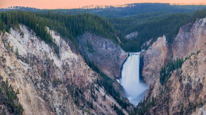 Waterfall cascading into a canyon with pine trees