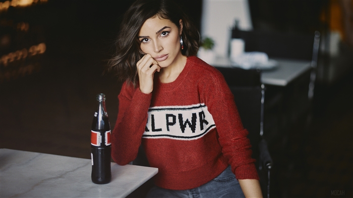 Olivia Culpo wearing a red sweater with "GIRL PWR" text