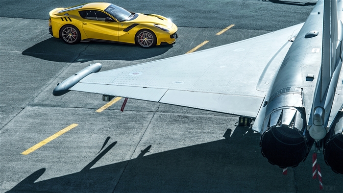 Yellow Ferrari F12tdf next to a fighter jet wing