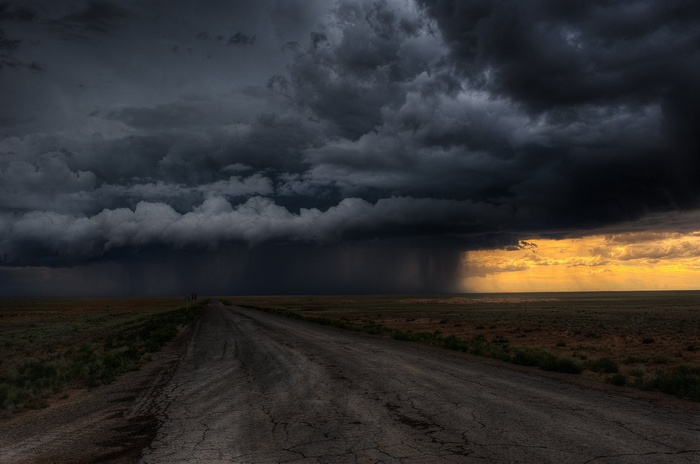 Stormy sky over a dirt road in a field