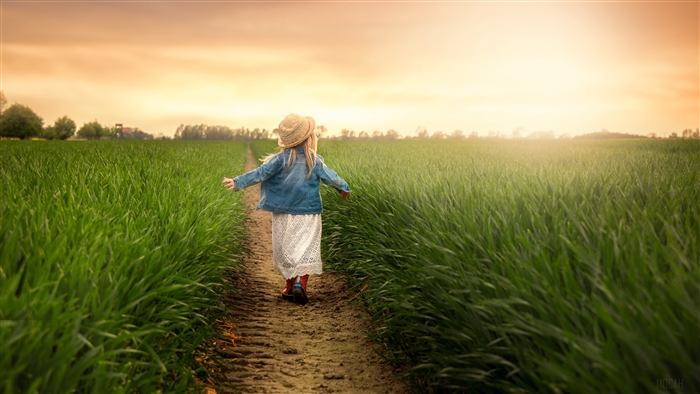 Girl in straw hat walks on path through grass field 4K